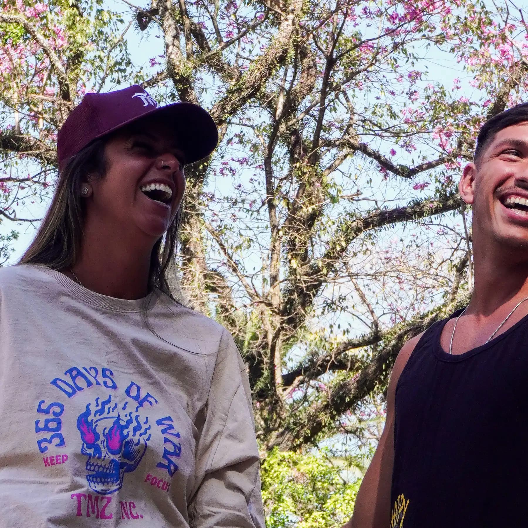 Casal vestindo peças TMZ sob os ipês